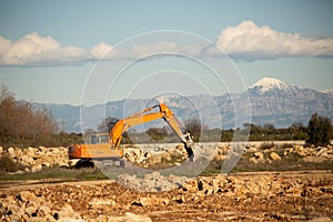 Crawler excavator clearing piles of rocks. Orange color machine