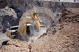 Yellow excavator is filling a dump truck with rocks at coal mines