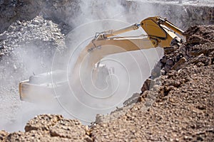 Yellow excavator is filling a dump truck with rocks at coal mines