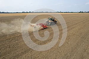 Crawler tractor harrowing and leveling soil for next seeding in rural plain fields