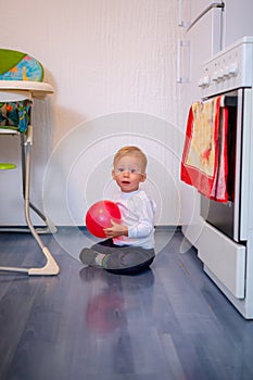 Crawling baby boy playing with balloon at home