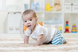 Crawling funny baby boy in nursery at home