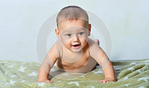 Crawling funny baby indoors at home. Family morning at home. Textile and bedding for kids. Cute happy baby lying and