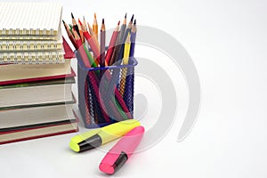 Crayon or colored pencils in box with side stack of books and school supplies. Concept of learning and study.