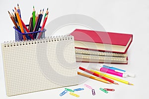 Crayon or colored pencils in box with side stack of books and school supplies on with background..