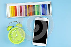 Crayon green clock and mobile on blue background pastel style to