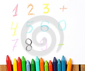 Crayons lying on a paper with painted digit, number, sign