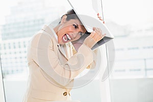 Crazed businesswoman hitting head off laptop