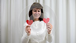 Crazy adult senior celebrate Valentine's Day. Woman cover eyes with red valentine cards and smile. Romantic