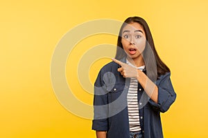 Crazy advertisement! Portrait of amazed shocked girl in denim shirt pointing to side copy space, gesturing attention