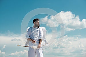 Crazy angel cupid valentin with bow arrow ready to shoot. Funny bearded man with feathers wings of Cupid Valentines Day.