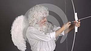 Crazy angel cupid valentin with bow arrow ready to shoot. Funny bearded man with feathers wings of Cupid Valentines Day.