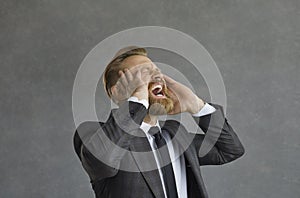 Crazy and angry Caucasian businessman in anger screams loudly and angrily grabbing his head.