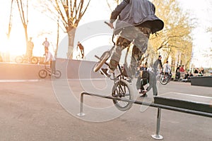 Crazy BMX rider performs tricks in the skate park on the background of the sunset. Jump on the bike
