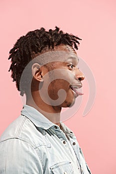 The crazy business Afro-American man standing and wrinkle face pink background. Profile view.