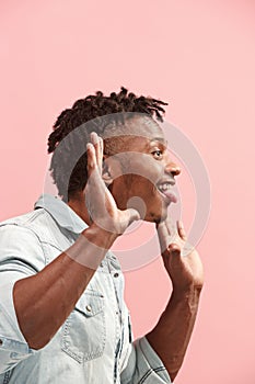 The crazy business Afro-American man standing and wrinkle face pink background. Profile view.