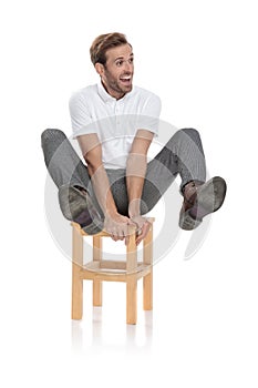 Crazy casual man sitting and holds legs in the air