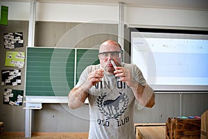 A crazy chemistry teacher in goggles sniffs reagents from a test tube