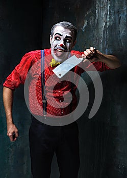 The crazy clown holding a knife on dack. Halloween concept