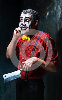 The crazy clown holding a knife on dack. Halloween concept