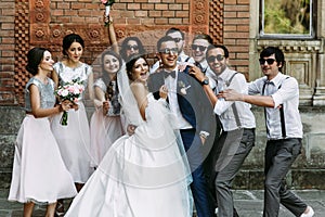 Crazy couple and bridesmaids with groomsmen behind photo