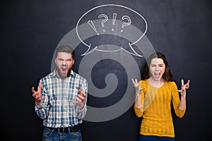 Crazy couple screaming over chalkboard background