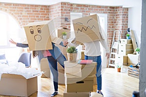 Crazy couple wearing boxes with funny faces over head, having fun happy for moving to a new house