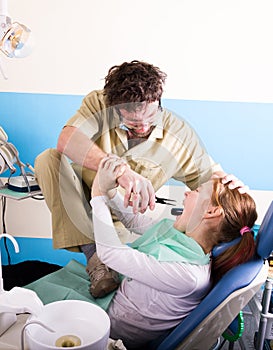 Crazy dentist treats teeth of the unfortunate patient. The patient is terrified.