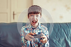 Crazy dependent kid shouting while playing video game photo