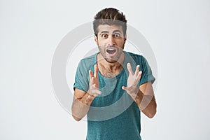 Crazy desperate good-looking man being shocked looking at camera with wide opened mouth and bugged eyes shouting with