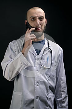 Crazy doctor displays funny grimace while using the phone and having stethoscope displayed
