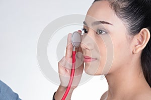 Crazy doctor`s hand holding stethoscope for checkup woman`s face