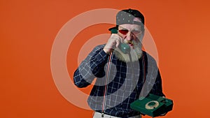 Crazy elderly bearded old man talking on wired vintage telephone of 80s, fooling, making silly faces
