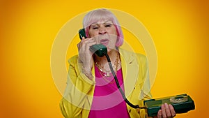 Crazy elderly granny old woman talking on wired vintage telephone of 80s, fooling making silly faces