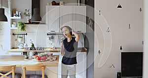 Crazy energetic young playful woman having fun in kitchen.