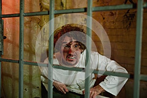 Crazy forsaken man sitting in bathroom behind cage gate photo