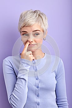 Crazy funny adult woman picking out boogers, drilling nose, looking at side