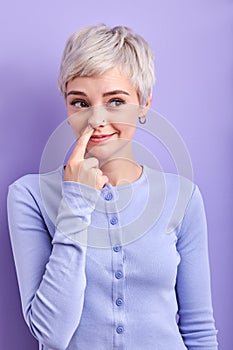 Crazy funny adult woman picking out boogers, drilling nose and smiling