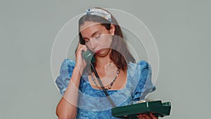 Crazy girl in blue dress talking on wired vintage telephone of 80s, fooling making silly faces