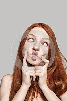 Crazy girl Close up photo of happy young redhead woman making crazy face and grimacing while standing against grey