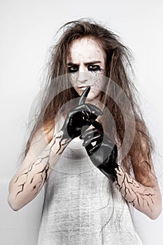 Crazy girl with disheveled hair, black eyes and veins shows her finger shh. Halloween concept.