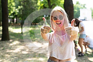Crazy girl with powder paints on her face celebrating Holi color festival shows class. Portrait of a girl in the park at