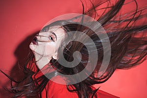 Crazy girl waving her hair. Woman with stylish makeup and long hair posing in total red outfit. Fashion concept. Girl on