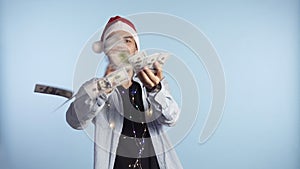 Crazy, handsome excited man throwing dollar banknotes and smiling. Squandering, wealth. Man in a santa red hat and
