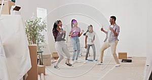 Crazy happy family painting the walls with white paint with brushes, they dance in the