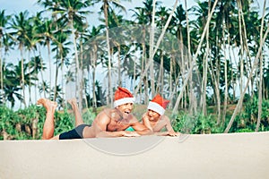 Crazy happy father and son lie on tropical sand beach in Sants h