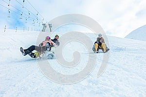 Crazy happy friends having fun with sledding on snow high mountains - Young millennial people making luge competition at white