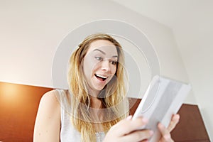 Crazy happy young woman working smilling with tablet at white bed
