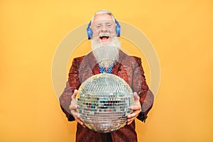 Crazy hipster man listening music with headphones while holding disco ball - Party concept photo