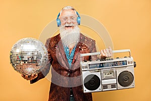Crazy hipster man listening music with headphones while holding disco ball and vintage stereo - Party concept photo